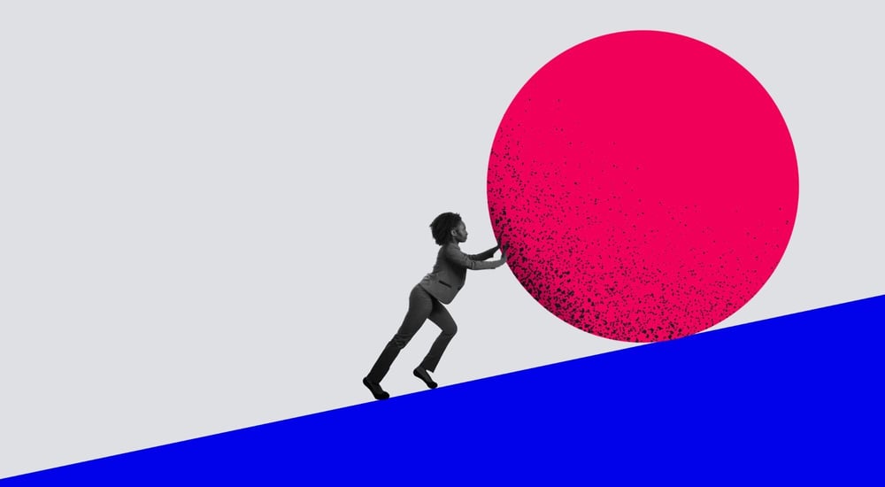 A woman pushing a boulder up a hill